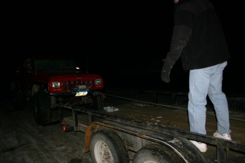 2003 Jeep TJ - A red Jeep Cherokee XJ is loaded onto a trailer at night.