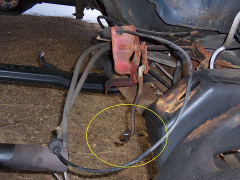 1987 Ford Bronco - Undercarriage view showing various mechanical components and wiring, with a focus on a specific part highlighted by a yellow circle.