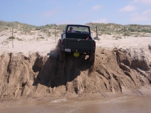 1985 Toyota Hilux - A pickup truck navigates a steep sand dune on a sunny day.