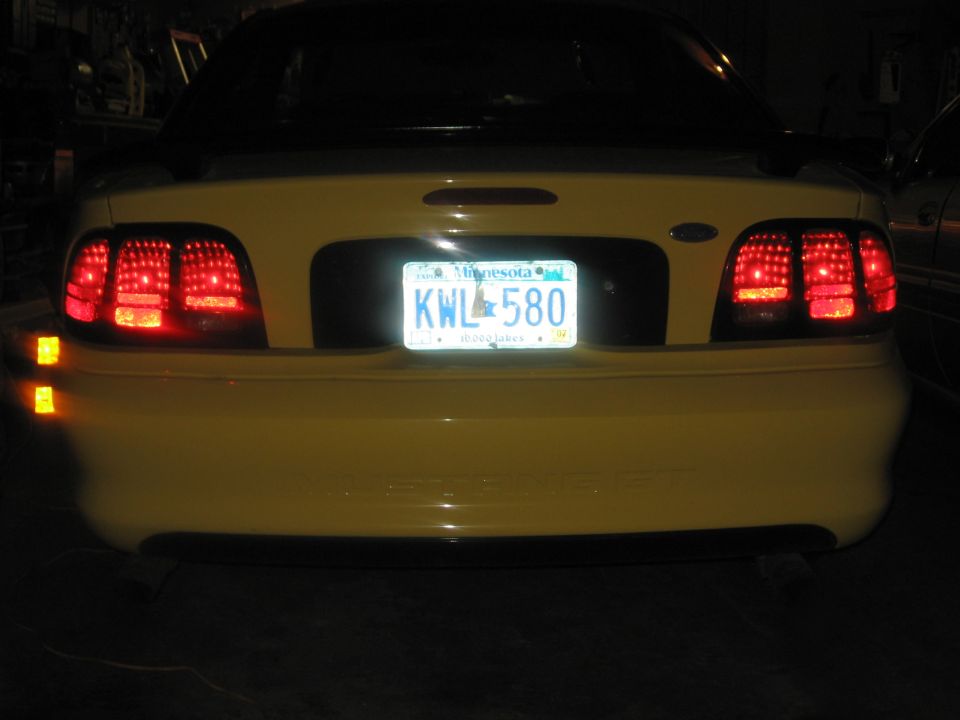 Yellow 1994 Ford Mustang rear view with clear taillights and a Minnesota license plate