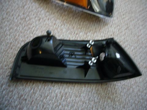 2000 Ford Crown Victoria - A black plastic car part, possibly a corner light housing, is shown against a carpeted background.