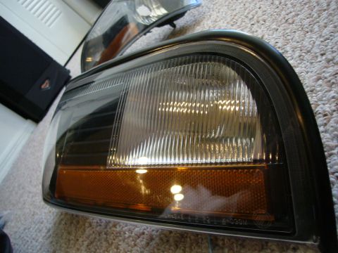 2000 Ford Crown Victoria - Car headlight assembly with amber turn signal section and ribbed clear lens.