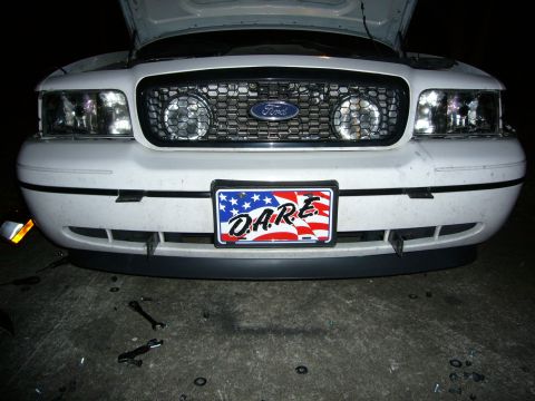 2000 Ford Crown Victoria - Night shot of the front end of a white Ford Crown Victoria with the hood raised, showing the honeycomb grille with blue Ford oval, round dr…