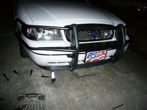 2000 Ford Crown Victoria - Front view of a 2000 Ford Crown Victoria equipped with a push bar, with tools scattered on the ground.
