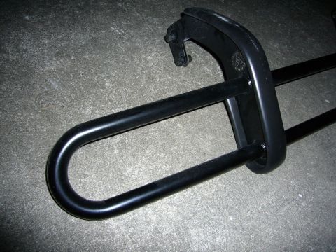 2000 Ford Crown Victoria - Black powder-coated tubular steel assembly laid on a concrete floor: a long U-shaped hoop passing through a formed bracket secured with two…