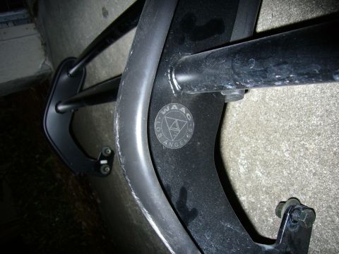 2000 Ford Crown Victoria - Close-up of a black powder-coated tubular rack or bumper guard leaning against a stucco wall, with a round decal reading "WAAG · LOS ANGELE…