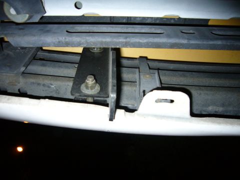 2000 Ford Crown Victoria - Night flash shot under the front bumper cover of a light-colored car, showing a bolted black steel bracket mounted to the bumper reinforcem…
