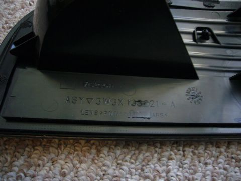 2000 Ford Crown Victoria - Close-up of a black automotive part showing embossed text and material designations.