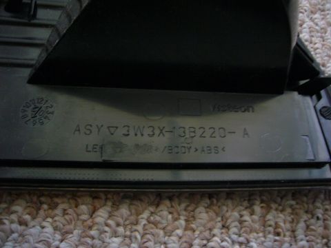 2000 Ford Crown Victoria - Close-up of a black plastic automotive part showing a date code and part number.