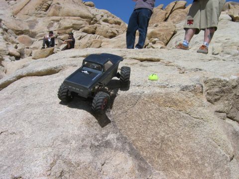 1985 Ford Bronco - This remote-controlled rock crawler, resembling a 1980s Ford Bronco, navigates a rocky terrain under a clear blue sky.