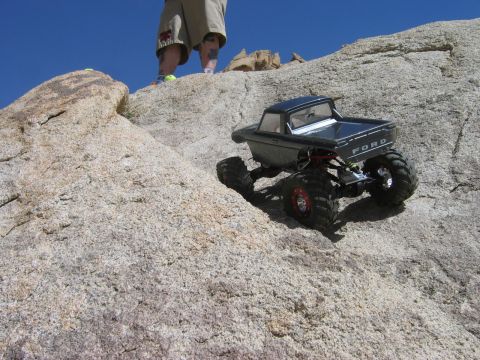 1985 Ford Bronco - A remote control truck navigates a challenging rocky terrain under a clear blue sky.