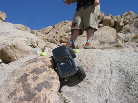 1985 Ford Bronco - A remote-controlled rock crawler, identified by "FORD" on its tailgate, navigates a challenging rocky landscape.