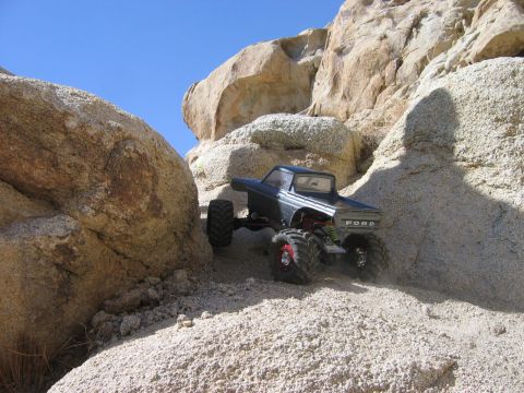 1985 Ford Bronco - Remote control monster truck with 'FORD' badging navigates rocky terrain.