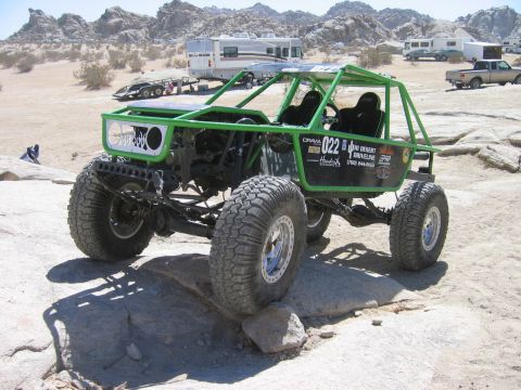 1985 Ford Bronco - Custom green buggy navigates rocky terrain with large off-road tires.