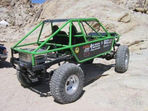 1985 Ford Bronco - This custom-built off-road buggy features a prominent green roll cage and large, tires, designed for challenging terrain.