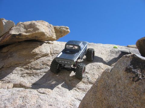 1985 Ford Bronco - A remote-controlled truck navigates a challenging rocky terrain under a clear blue sky.