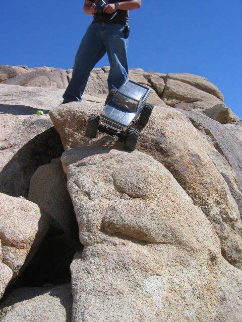 1985 Ford Bronco - RC rock crawler navigating a rocky terrain with a person controlling it.