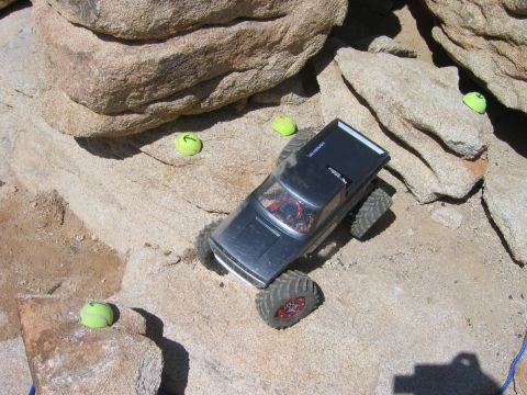 1985 Ford Bronco - A remote control truck navigates a challenging obstacle course made of rocks and sand.