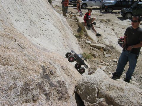 1985 Ford Bronco - A remote control rock crawler navigates a steep, rocky incline while spectators observe the action.
