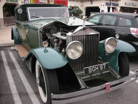 1998 Ford Crown Victoria - A vintage green Rolls-Royce with its hood open, parked next to a modern car. The license plate reads BGH 97.