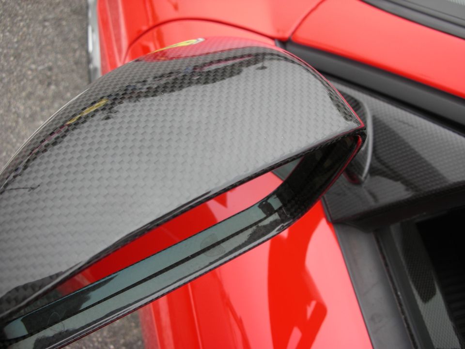 Carbon-fiber side mirror on a red sports car, close-up