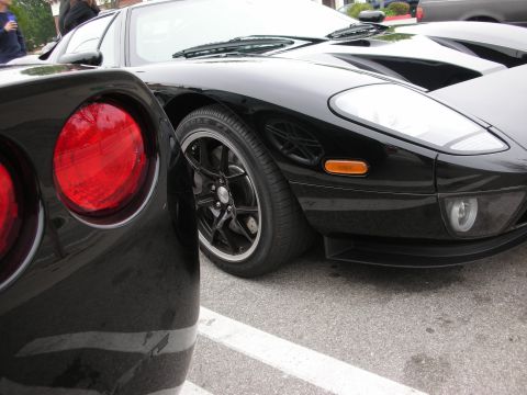 1998 Ford Crown Victoria - Close-up of two black sports cars, one showing its front end and the other its tail lights.