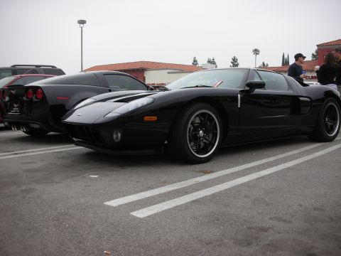1998 Ford Crown Victoria - A black Ford GT is parked in a lot next to another black car.
