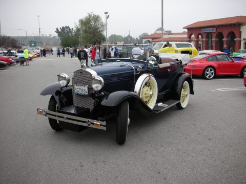 1998 Ford Crown Victoria - A dark blue 1928 Ford Model A convertible parked at a car meet with other vehicles visible.