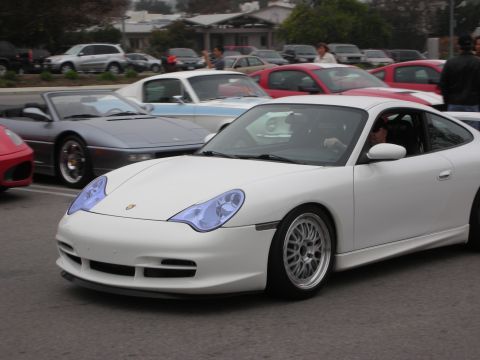 1998 Ford Crown Victoria - A white Porsche 911 is parked among other vehicles at a car meet.