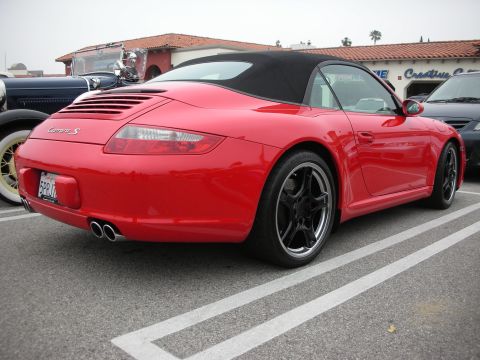 1998 Ford Crown Victoria - A red convertible sports car, identified as a Carrera S, is parked in a lot next to other vehicles.