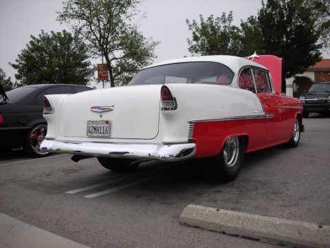1998 Ford Crown Victoria - Rear view of a classic 1955 Chevrolet Bel Air with its hood open, parked next to another car.
