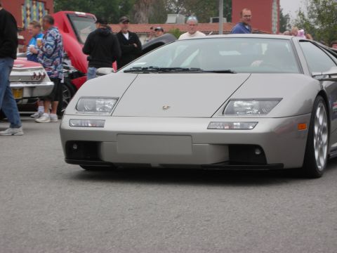 1998 Ford Crown Victoria - A silver Lamborghini Diablo is the main focus, with other vehicles and people gathered around.