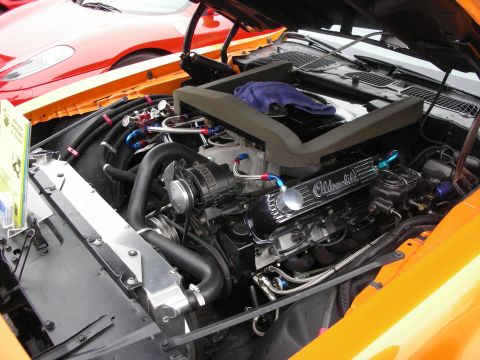 1998 Ford Crown Victoria - The engine bay of an orange car is shown, with another red car visible behind it.
