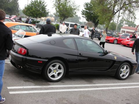 1998 Ford Crown Victoria - A black Ferrari 456 GT is parked at a car meet, with other vehicles in the background.