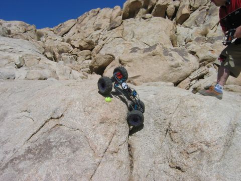 1985 Ford Bronco - A remote control rock crawler navigates a steep, rocky terrain under a clear blue sky.