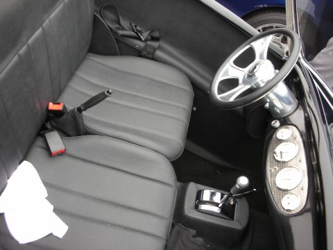1998 Ford Crown Victoria - The interior of a custom vehicle features black bucket seats, a chrome steering wheel, and a unique gauge cluster.