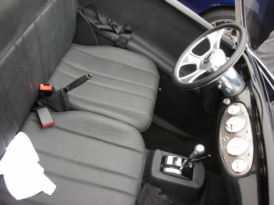 Custom roadster interior with gray bench seat, chrome shifter and turned-metal gauge panel