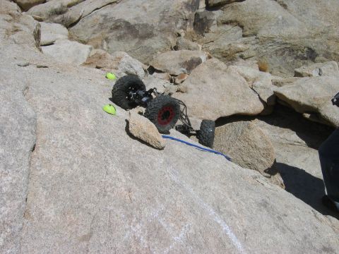 1985 Ford Bronco - A remote control rock crawler navigates a challenging rocky terrain, marked by yellow cones.