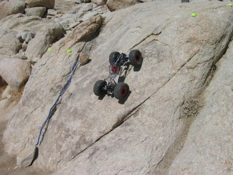 1985 Ford Bronco - RC rock crawler navigating a challenging rocky terrain course with yellow markers.