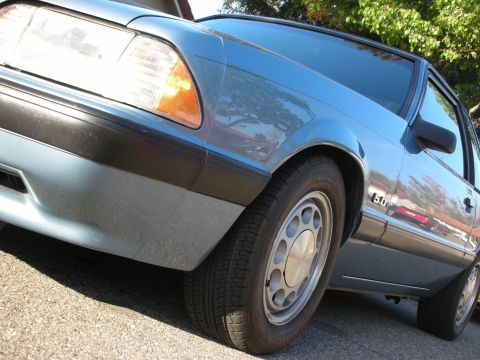 1990 Ford Mustang - A blue 1990 Ford Mustang is viewed from a low angle, highlighting the 5.0 fender badge.