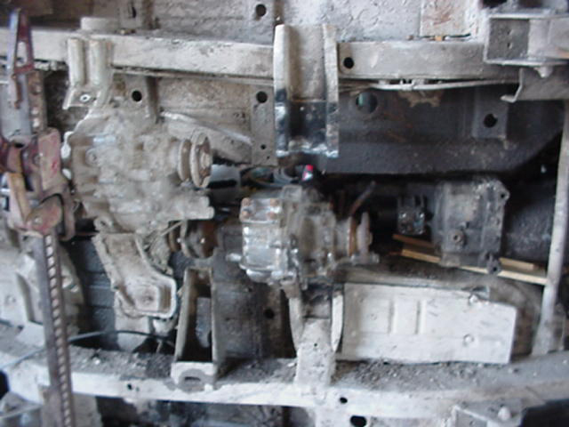 Undercarriage view of a vehicle showing a dual transfer case setup and suspension components
