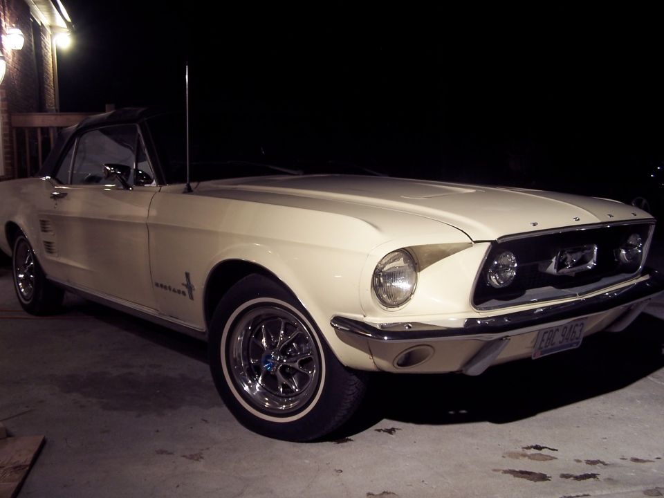 Cream classic Ford Mustang convertible with black top, front three-quarter view at night, plate EBC 9463