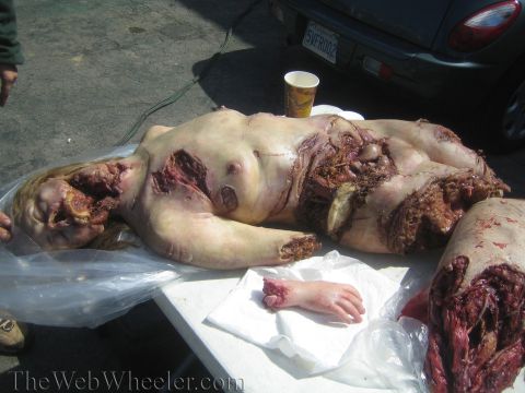 1990 Ford Bronco - Photo of a gory Halloween special-effects mannequin prop laid out on a table next to a car.