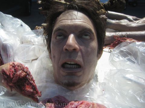 1990 Ford Bronco - Close-up of a realistic special-effects severed-head prop with bloody flesh, resting on plastic sheeting outdoors.