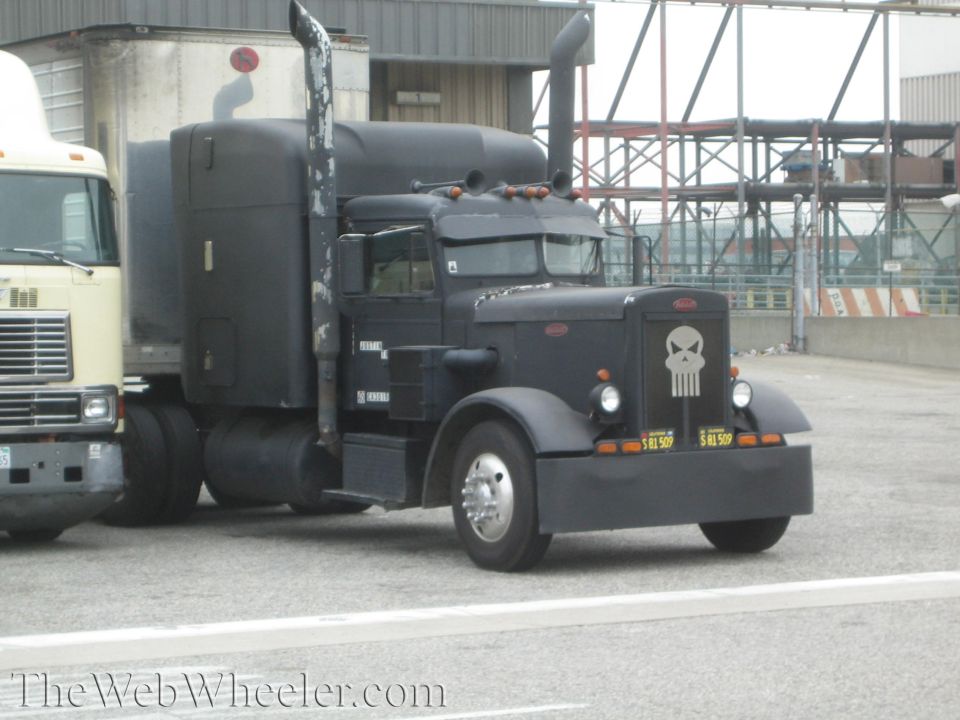 Flat-black Peterbilt semi truck with white skull graphic on the grille
