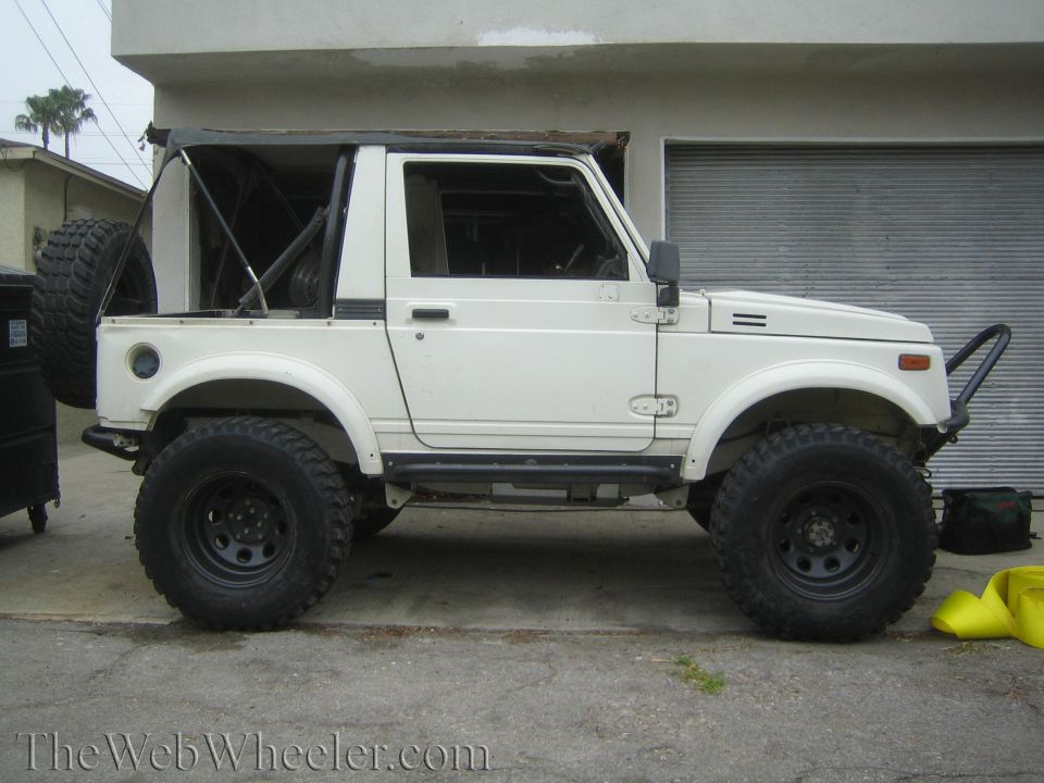 Side profile of lifted white Suzuki Samurai on black steel wheels with rock sliders