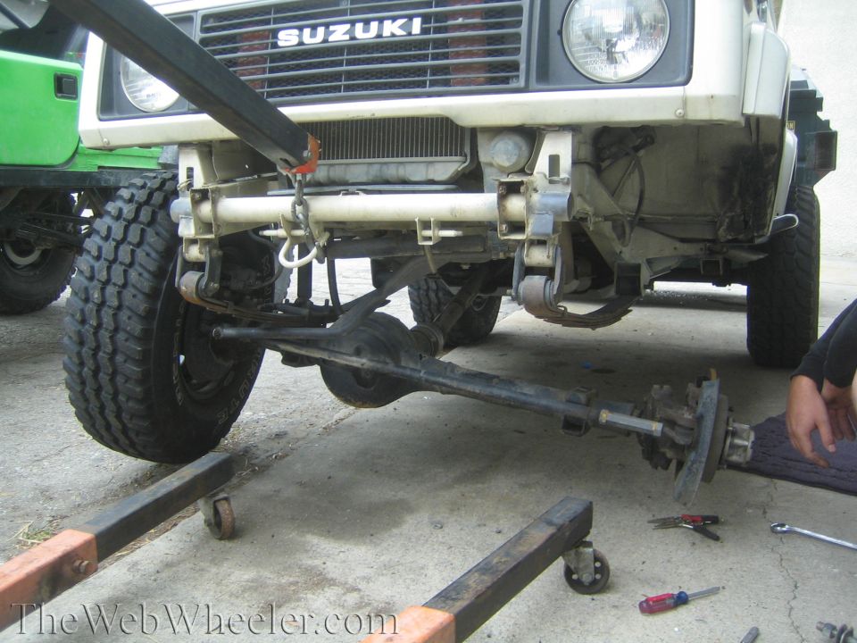 White Suzuki Samurai with front axle removed and lying on the driveway during repair