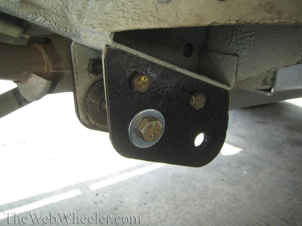 Black steel mounting bracket bolted to a frame with yellow-zinc bolts.