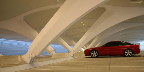 1993 Ford Probe - A red 1993 Ford Probe is parked in a unique, modern setting with distinctive white beams overhead.