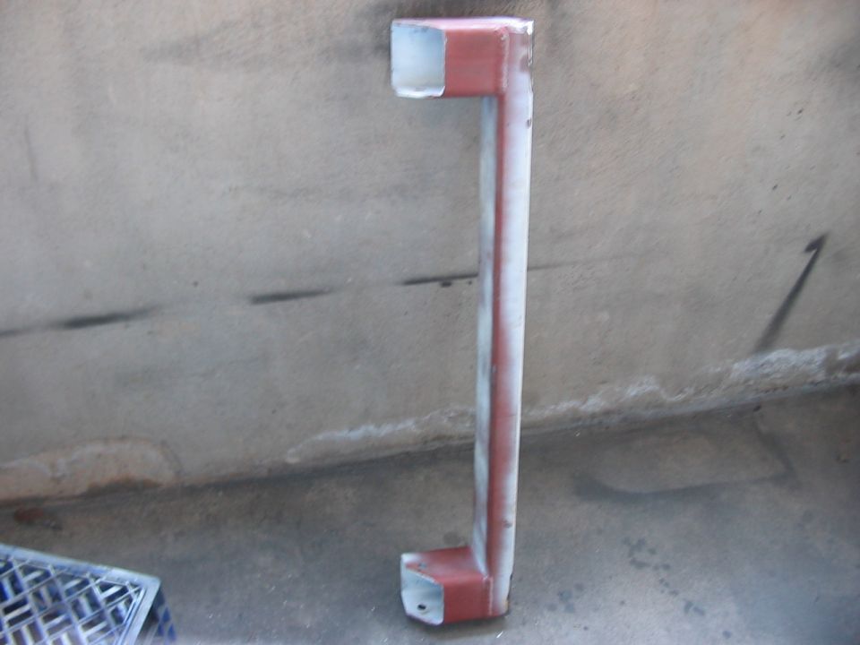Red and white painted metal pipe structure, L-shaped with square ends, on concrete